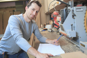 An adult carpenter measuring wood with ruler at table in workshop ** Note: Soft Focus at 100%, best at smaller sizes